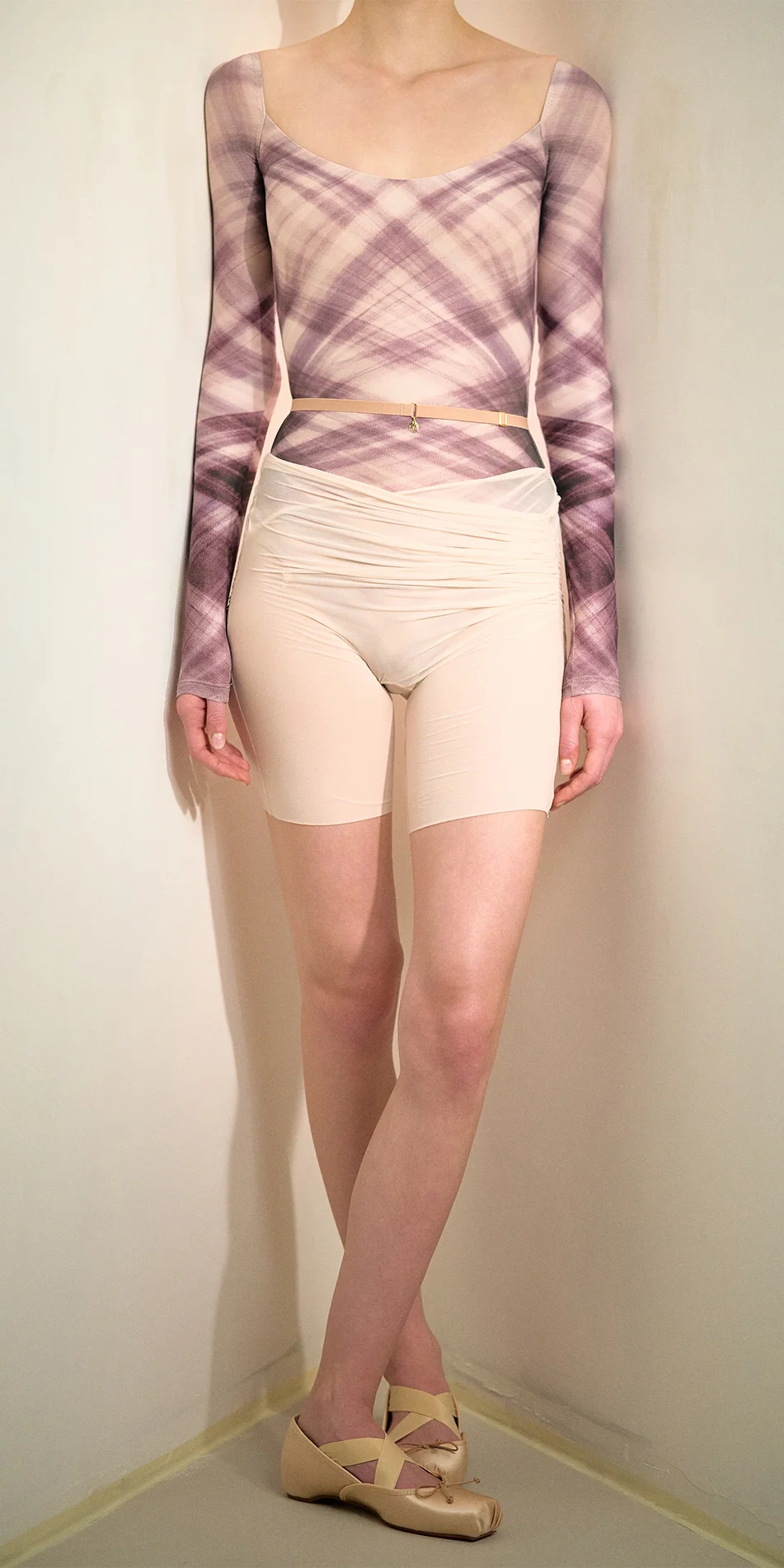 Sheer bike shorts in soft pink legs crossed close up